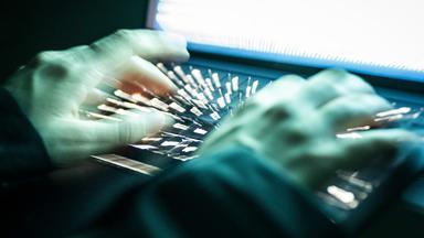 Eine Person tippt mit den Fingern auf einer beleuchteten Laptop-Tastatur. (Gestellte Szene, Aufnahme mit Langzeitbelichtung)