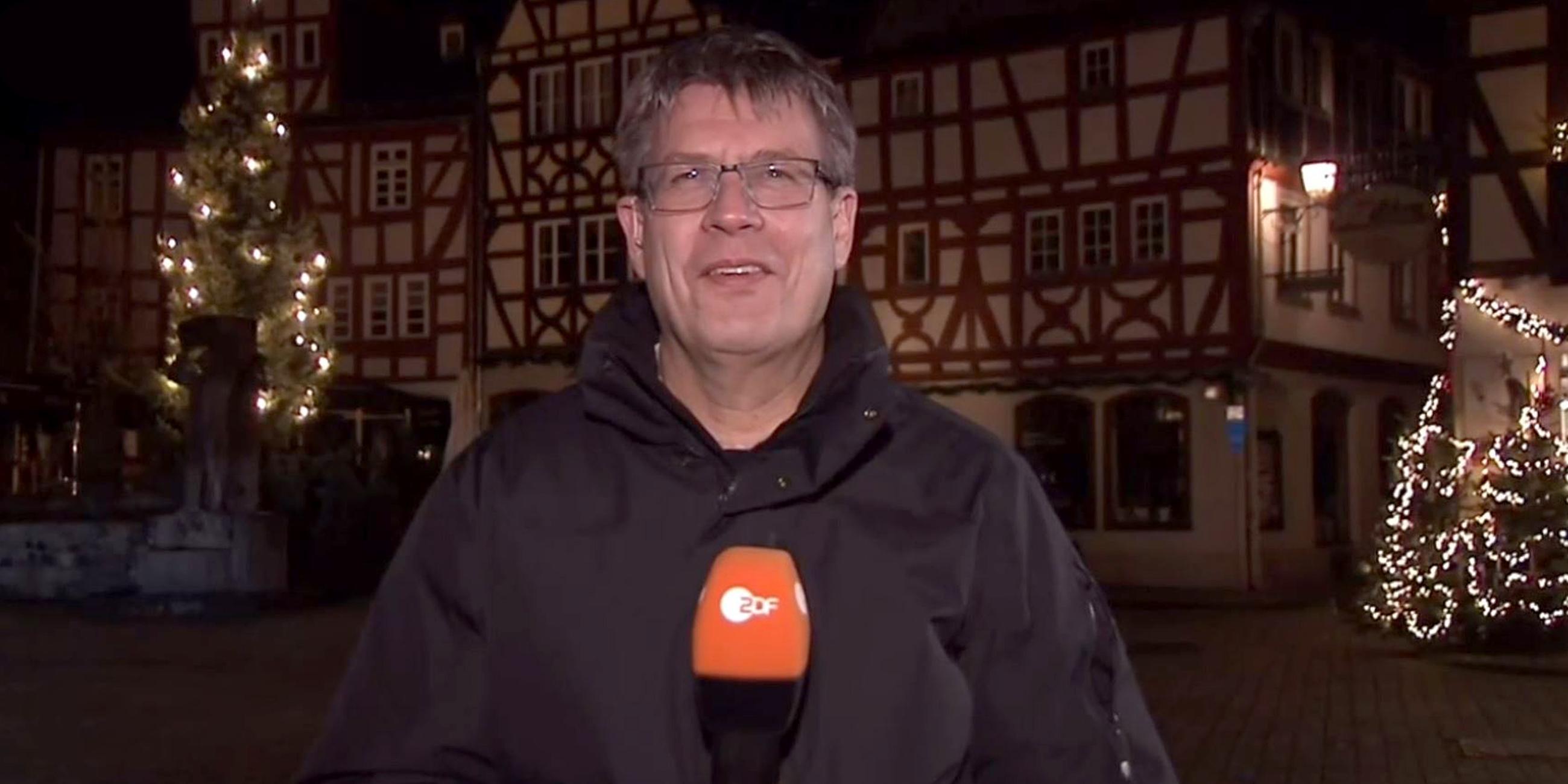 Thomas Weikert steht auf einem nächtlichen Altstadtplatz und hält ein Mikrophon in der Hand.