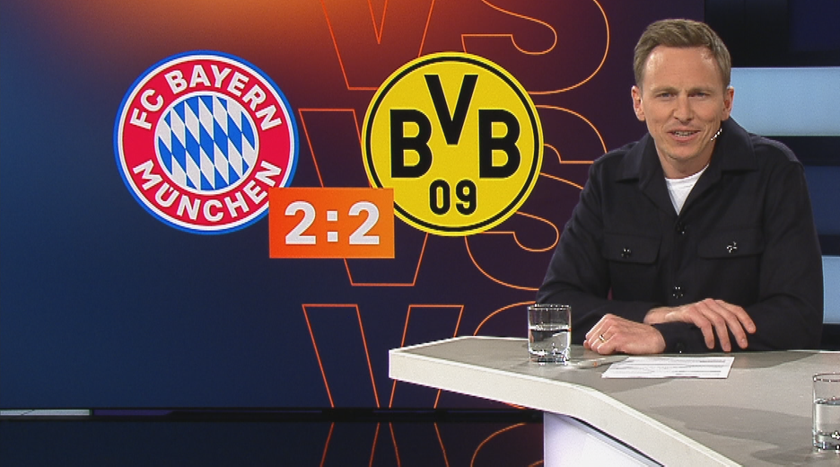 Der Moderator Jochen Breyer im aktuellen Sportstudio. Im Hintergrund das Topspiel zwischen Bayern München und Borussia Dortmund.