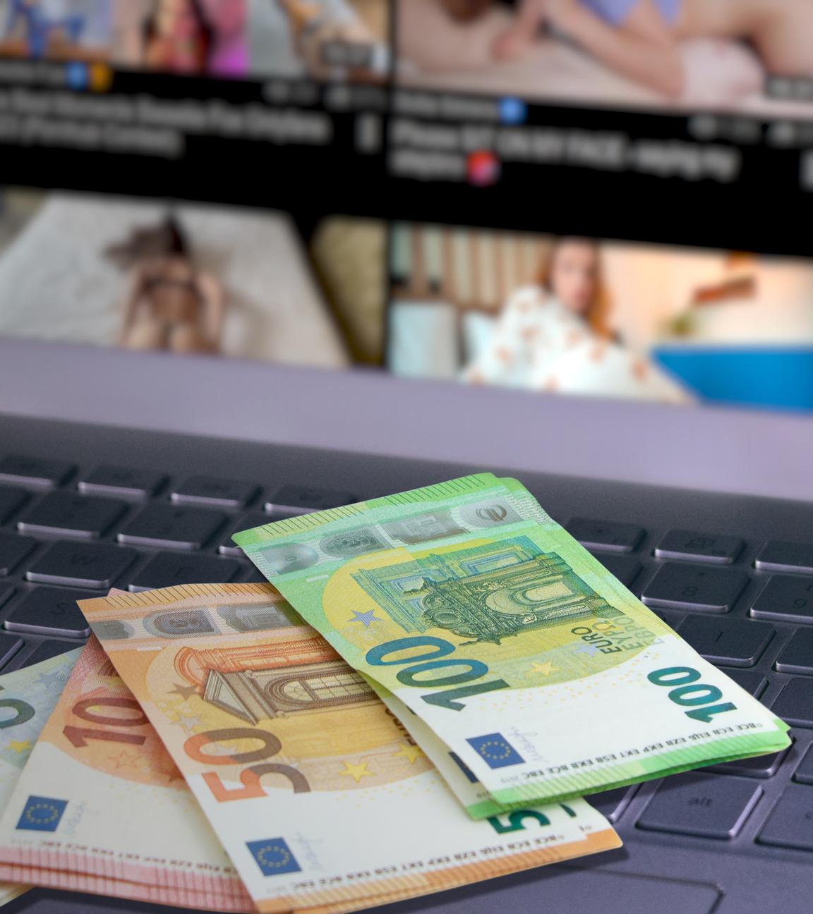 Auf einem geöffneten Laptop ist die Pornoseite "Pornhub" aufgerufen. Auf einer Taste des Laptops steht "PORN"; daneben liegen einige Geldscheine auf der Tastatur.