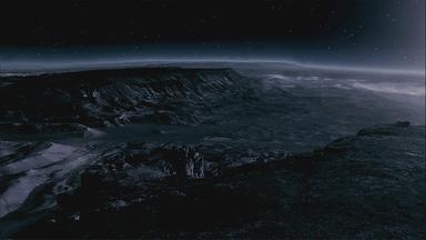 In der Dunkelheit ist eine raue Landschaft in einer bergigen Umgebung zu sehen. Im Hintergrund sind Sterne am Himmel.