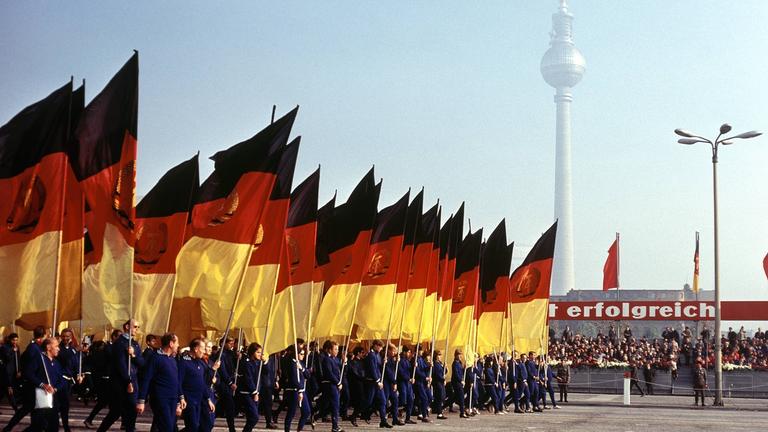 Demonstrationszug mit DDR-Fahnen.