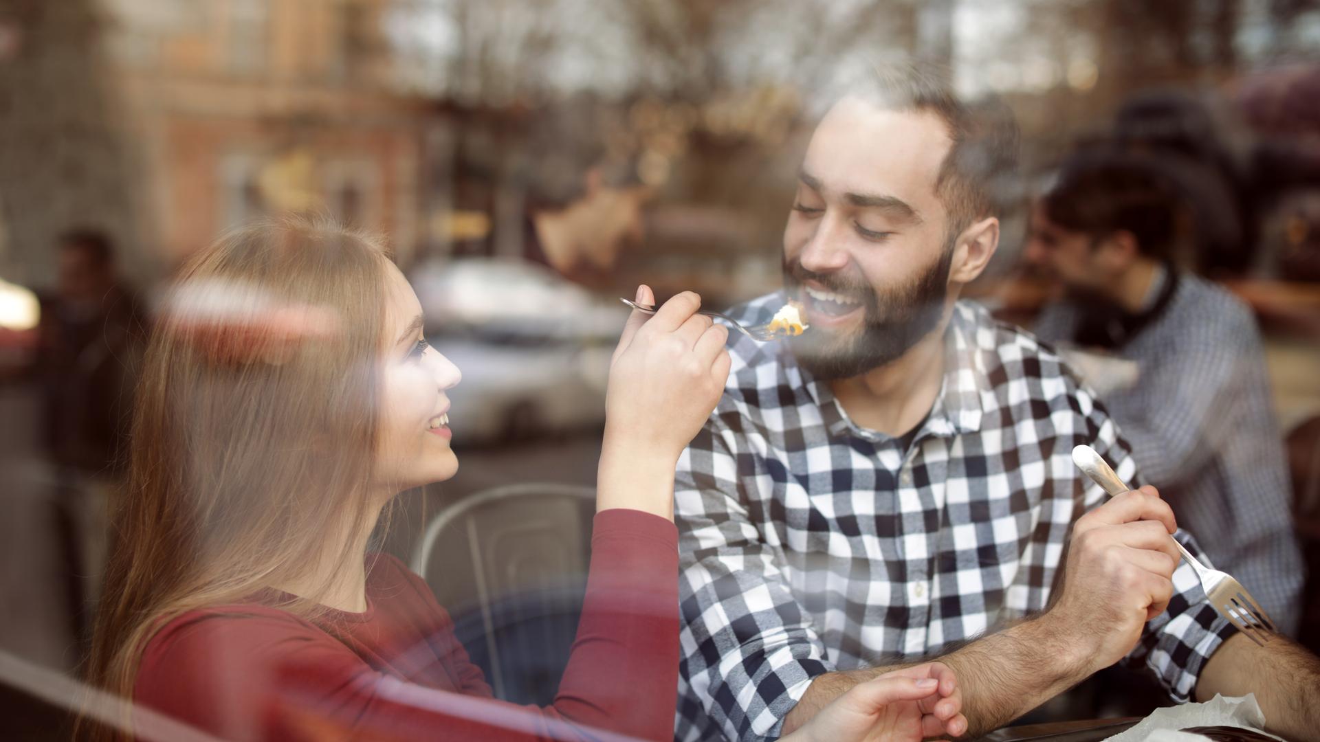 Paar im Café hinter einer Glasscheibe