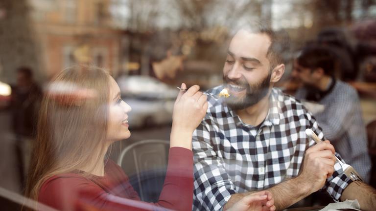 Paar im Café hinter einer Glasscheibe