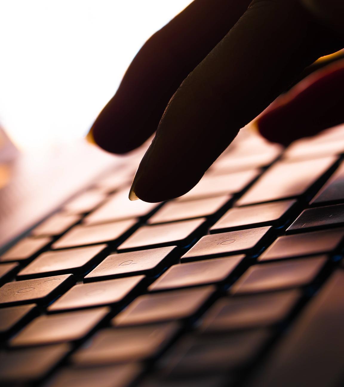 Hand im Dunkeln auf Laptop-Tastatur