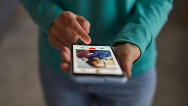 Eine Frau hat auf ihrem Smartphone eine Dating-App geöffnet.
