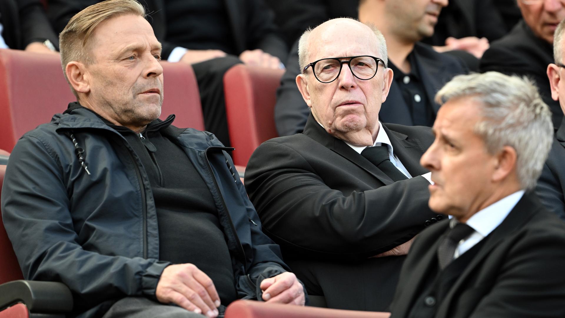 Bei der Trauerfeier für den früheren Bundesliga-Trainer Christoph Daum am 12.09.2024 im RheinEnergieStadion sitzen Thomas Heßler, Reiner Calmund und Pierre Littbarski (von Links) auf der Tribüne.