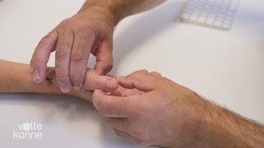 Arzt betatstet Daumen einer Patientin