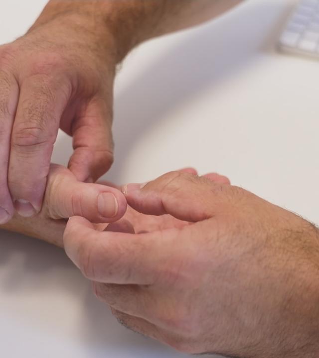 Arzt betatstet Daumen einer Patientin