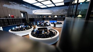 Auf einer Anzeigetafel wird die Kurve des deutschen Aktienindex (DAX) in der Frankfurter Börse im Hintergrund dargestellt.