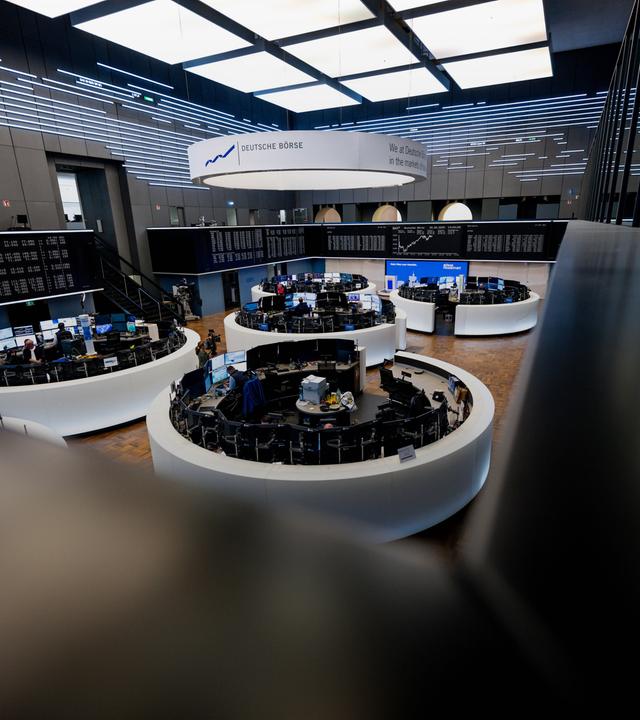 Auf einer Anzeigetafel wird die Kurve des deutschen Aktienindex (DAX) in der Frankfurter Börse im Hintergrund dargestellt.