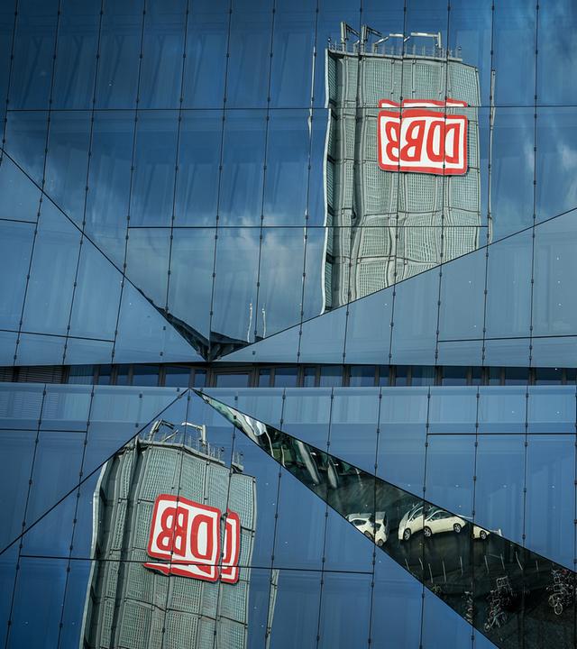Ein Gebäude mit dem Logo der Deutschen Bahn spiegelt sich in einem Bürogebäude am Berliner Hauptbahnhof.