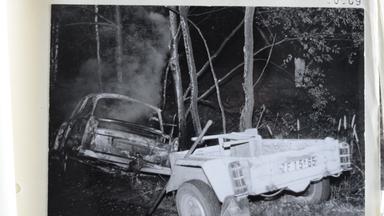 Ein abgebrannter Trabi mit Anhänger liegt nach einem Unfall in einem Wald.