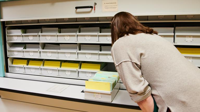 Berlin: Eine Besucherin schaut sich in einem Aktenraum der ehemaligen Stasi-Zentrale, Campus für Demokratie, in einem Karteikasten Unterlagen an.