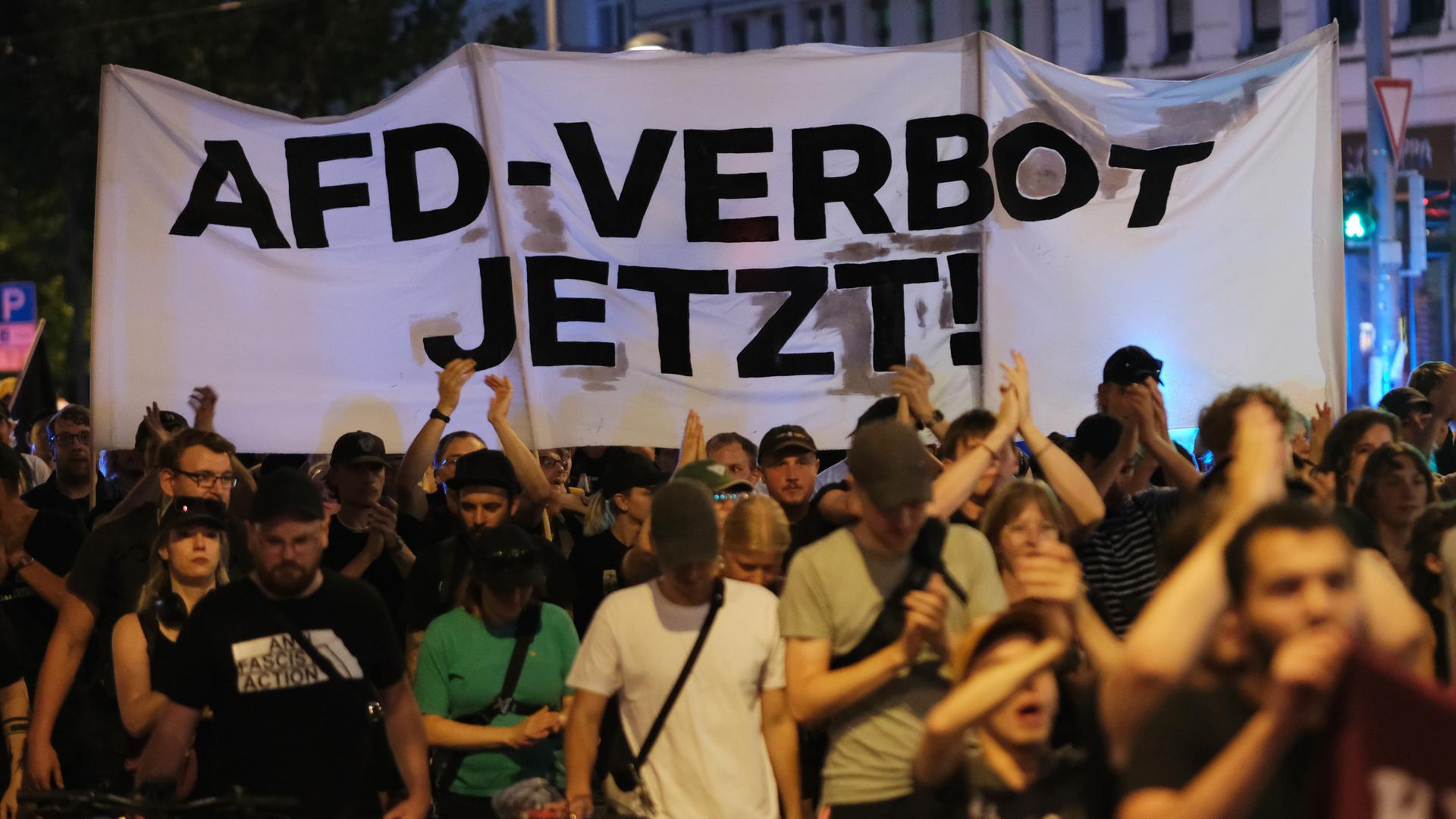 Sachsen, Leipzig: Teilnehmer einer linken Demonstration gehen mit Transparent mit der Aufschrift "AfD-Verbot jetzt!" eine Straße entlang. 