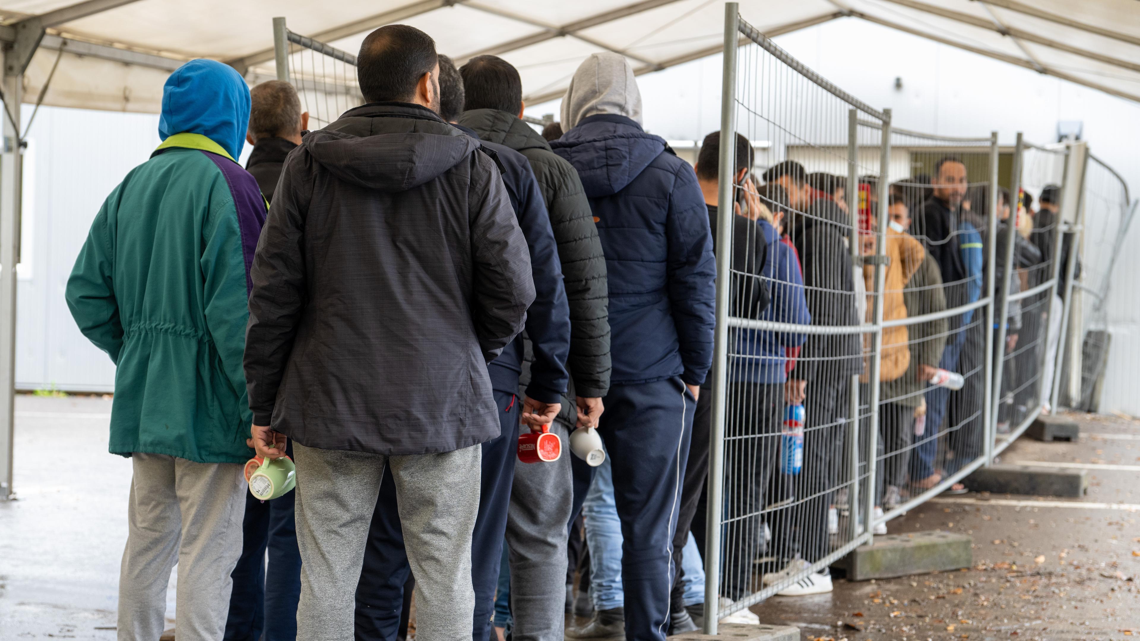 ARCHIV - 16.11.2022, Baden-Württemberg, Ellwangen: In der Landeserstaufnahmestelle (LEA) warten Flüchtlinge in einer Schlange vor der Essensausgabe. 