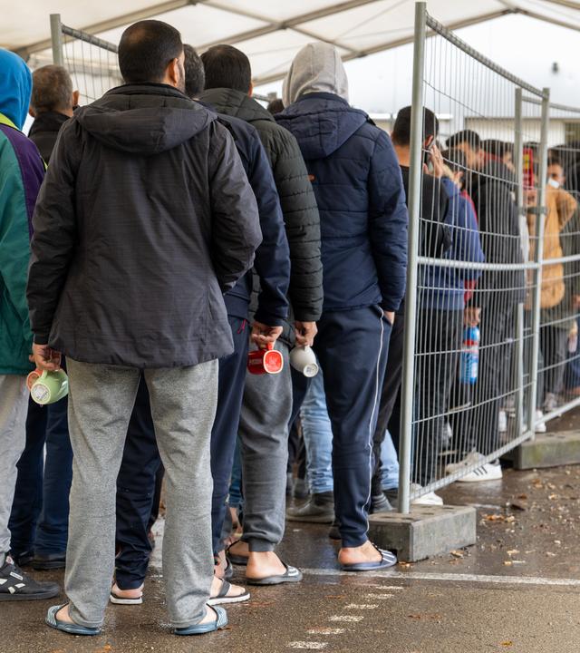 ARCHIV - 16.11.2022, Baden-Württemberg, Ellwangen: In der Landeserstaufnahmestelle (LEA) warten Flüchtlinge in einer Schlange vor der Essensausgabe. 