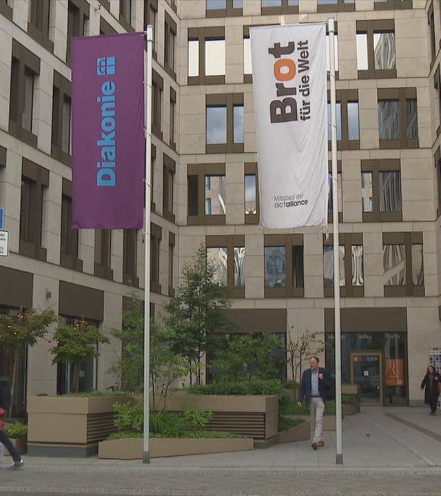 Gebäude der Diakonie von vorne, drei Fahnen im Vordergrund