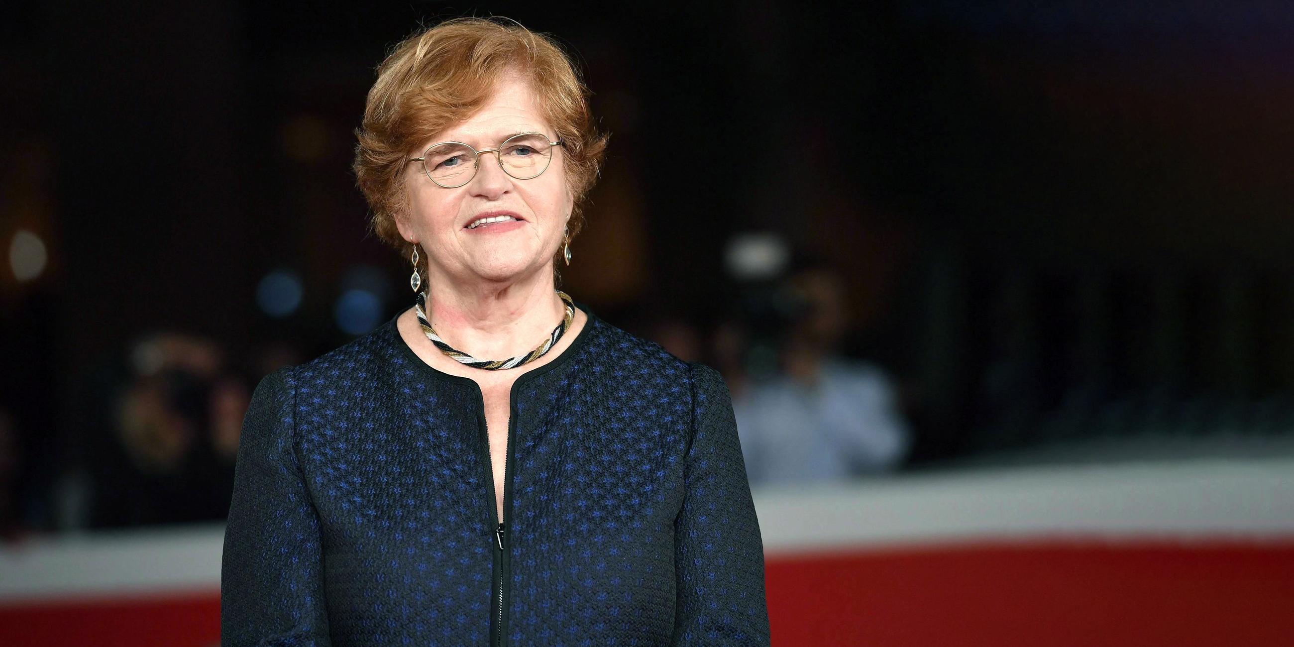 Eine Frau mit Brille und blauer Jacke und Schmuck