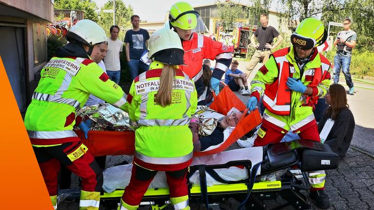 Rettungskräfte kümmern sich um einen Mann, der auf einer Liege liegt