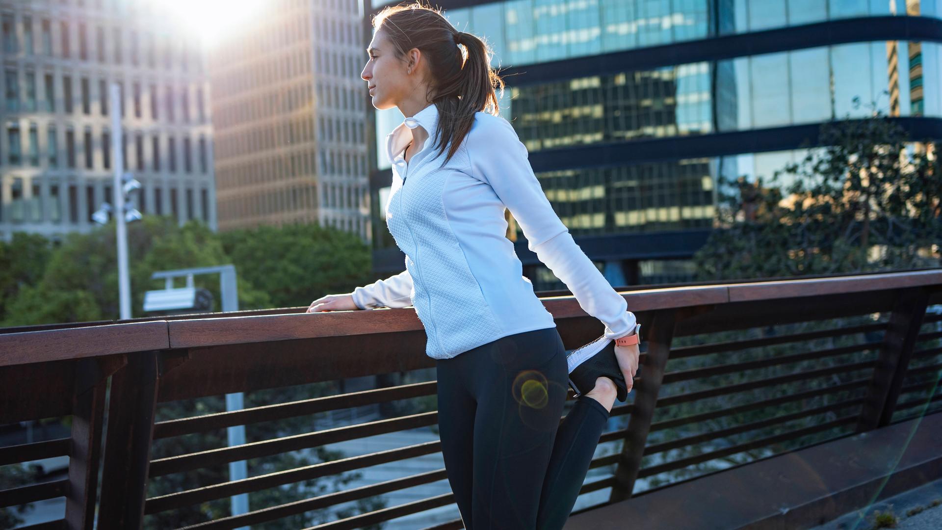 Joggerin bei einer Dehnübung vor einem Lauf in der Stadt