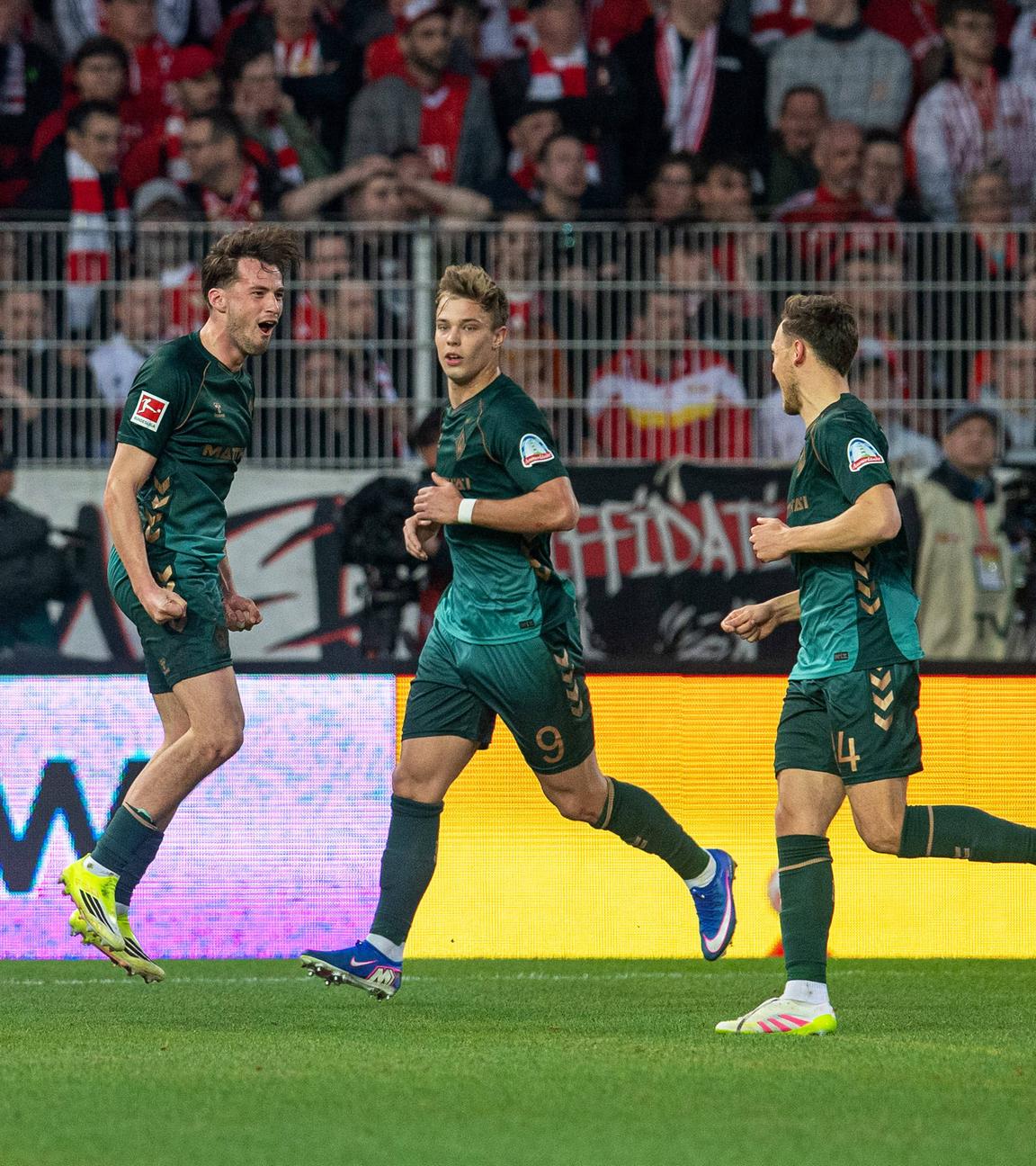 Bremens Abwehrspieler Olivier Deman jubelt zusammen mit seinen Teamkameraden Keke Topp und Senne Lynen nach seinem 1:1 Ausgleichstreffer gegen Union Berlin