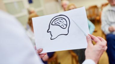Ärztin mit einer Zeichnung vom Gehirn hält einen Vortrag über Demenz und Gedächtnis