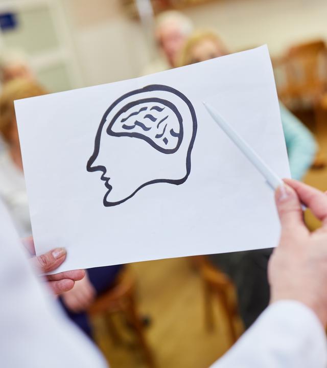 Ärztin mit einer Zeichnung vom Gehirn hält einen Vortrag über Demenz und Gedächtnis