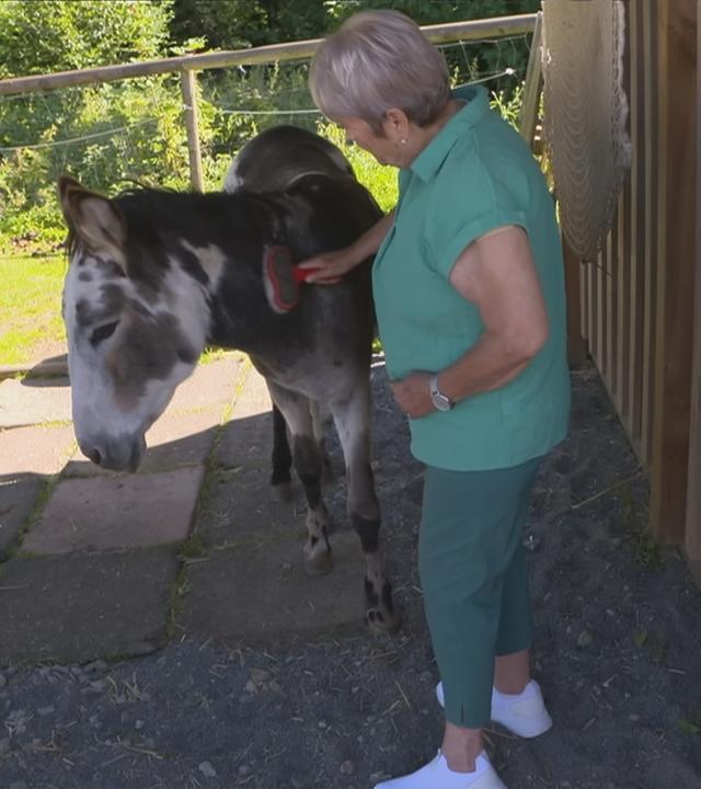 Bewohnerin des Demenzdorfes streichelt ein Tier