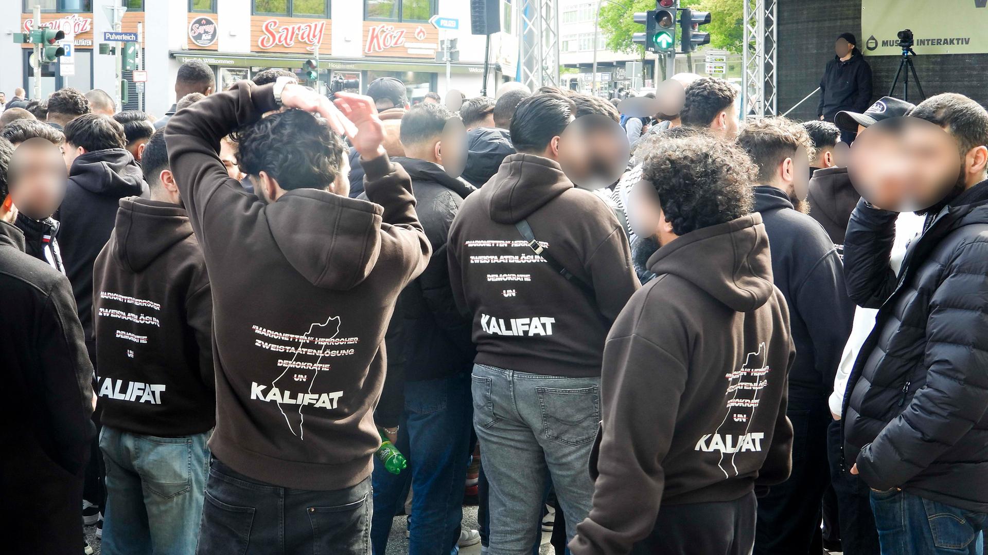 Demonstranten traten für Kalifat ein , auf ihren Jacken Mehrere hundert Demonstranten mit weissen Fahnen Spruchbaendern Plakaten bei der Muslimaktiv Demonstration am Hamburger Steindamm