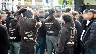 Demonstranten traten für Kalifat ein , auf ihren Jacken Mehrere hundert Demonstranten mit weissen Fahnen Spruchbaendern Plakaten bei der Muslimaktiv Demonstration am Hamburger Steindamm