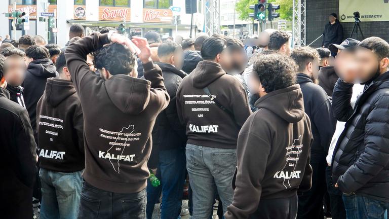 Demonstranten traten für Kalifat ein , auf ihren Jacken Mehrere hundert Demonstranten mit weissen Fahnen Spruchbaendern Plakaten bei der Muslimaktiv Demonstration am Hamburger Steindamm