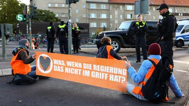 Klima-Aktivisten sitzen in Berlin auf der Straße und blockieren eine Straße, um für ein Tempolimit zu demonstrieren.