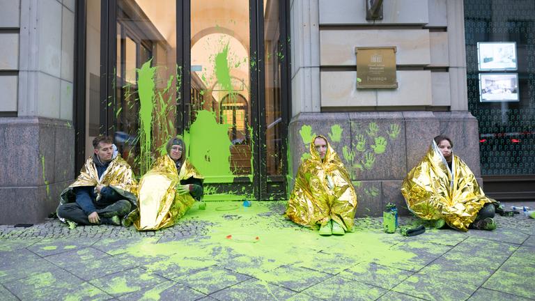 Berlin: Aktivisten der Letzten Generation sitzen während einer Demonstrationen gegen den "World LNG Summit" der Gasindustrie und Flüssiggasanbieter in Berlin