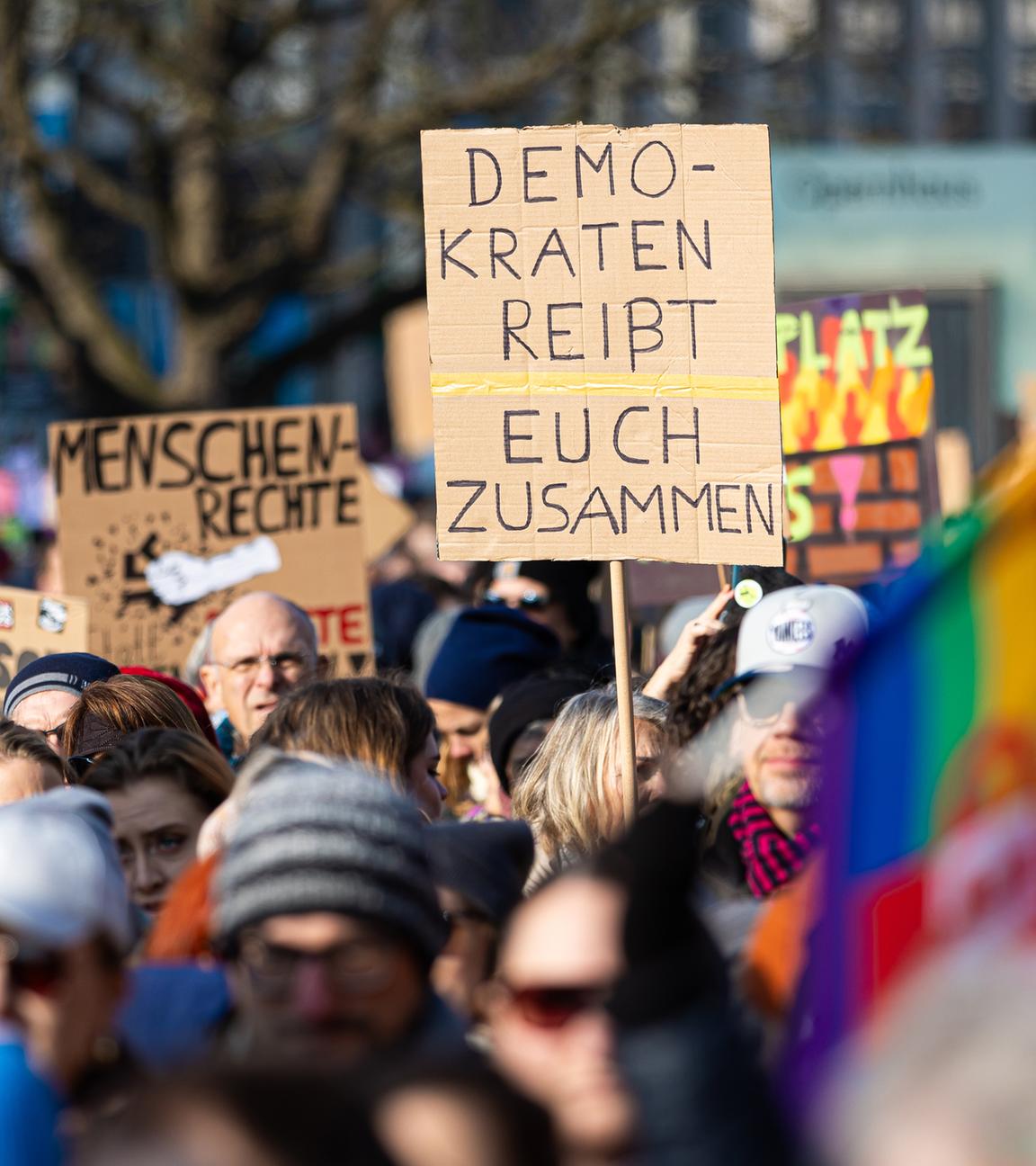 Bei einer Demonstration ist auf einem Plakat der Schriftzug "Demokraten reißt euch zusammen" zu sehen.
