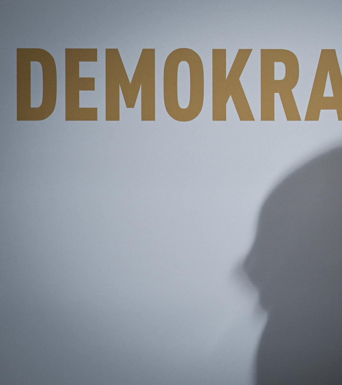 Berlin: Ein doppelter Schatten ist unter dem Schriftzug "Demokratie" zu sehen.