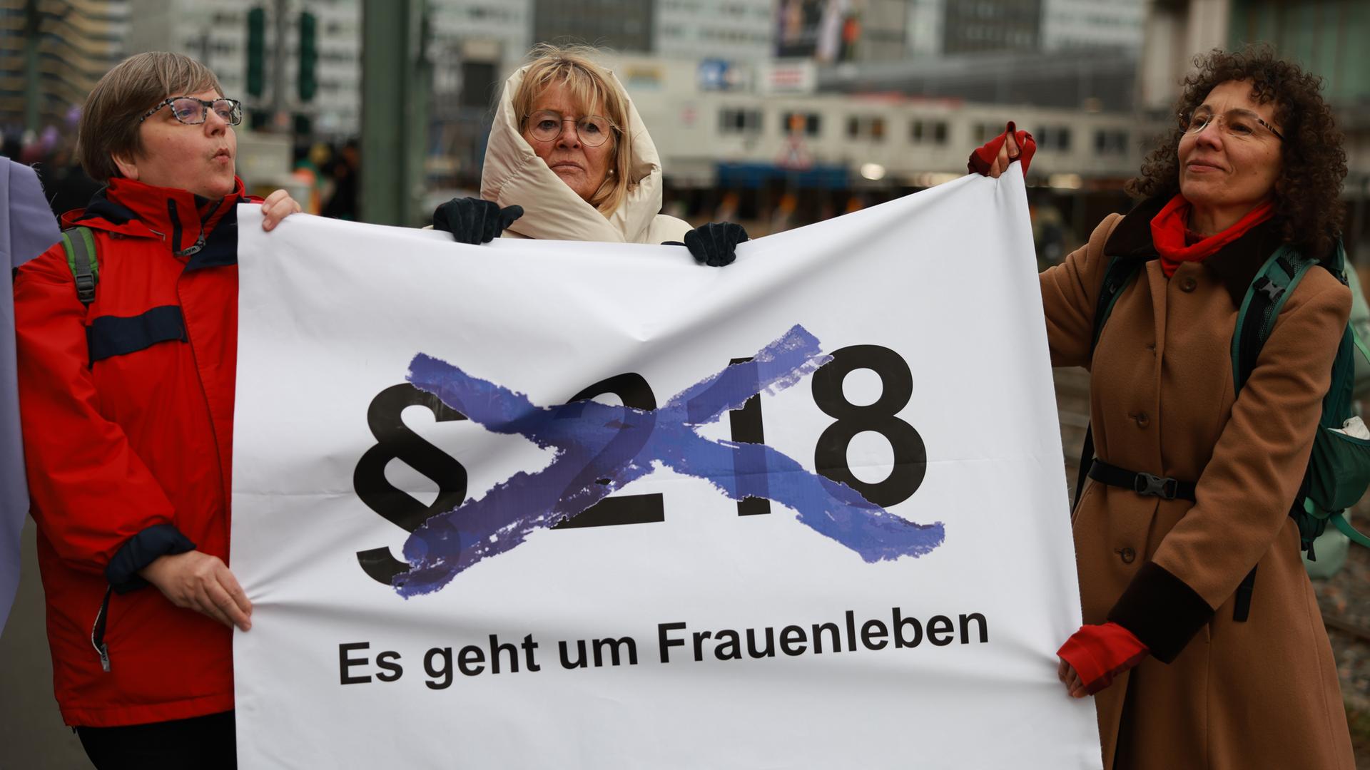 Demonstranten halten ein Transparent hoch, auf dem eine durchgestrichene Nummer des Paragraphen 218 zu sehen ist