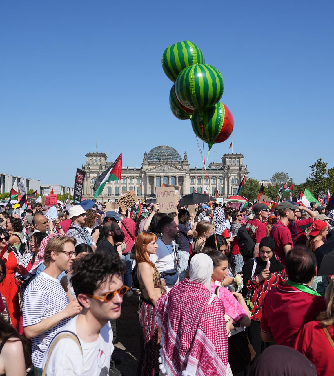 Viele protestierende Menschen, unteranderem mit palästinischen Flaggen. Im Hintergrund ist das Reichstagsgebäude.