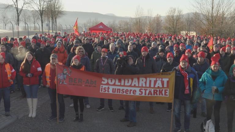 Bosch-Mitarbeitende demonstrieren gegen Arbeitsplatzabbau im baden-württembergischen Abstatt, halten im Vordergrund ein Transparent mit der Aufschrift: "Solidarität ist unsere Stärke"