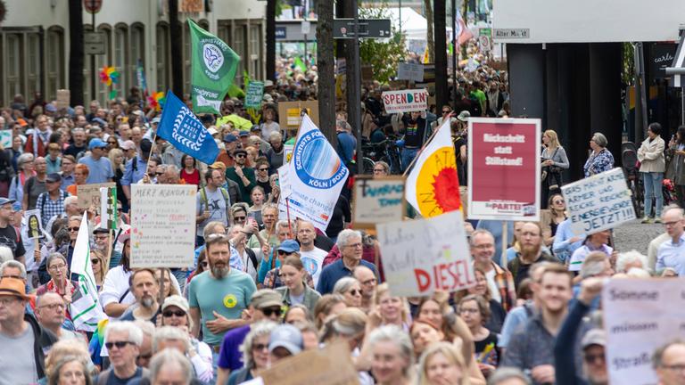 Demonstratanten ziehen durch Köln und halten Schilder hoch