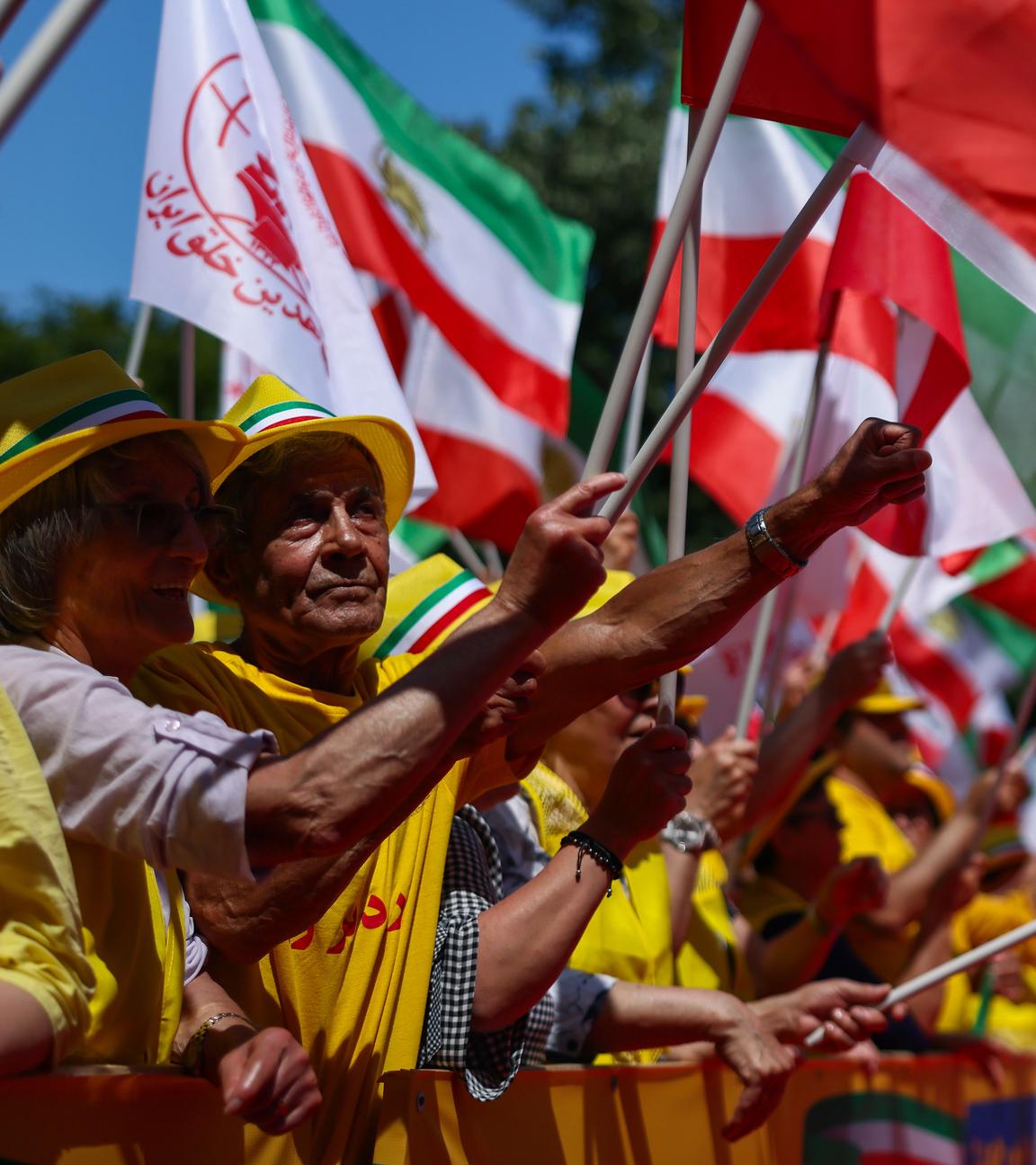 Bei einer Demonstration gegen die iranische Regierung halten Demonstranten Iran-Fahnen und Banner in die Luft.