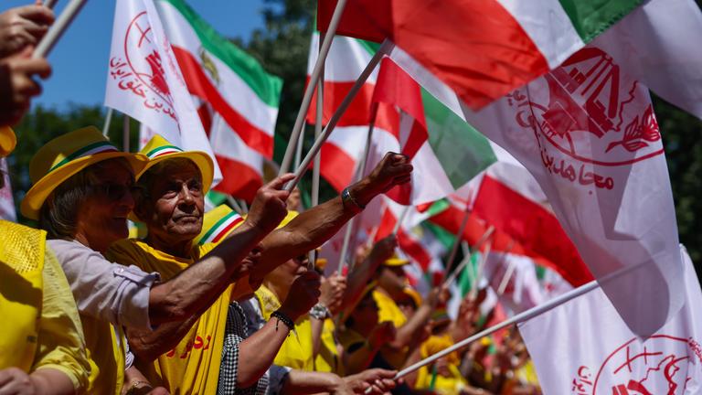 Bei einer Demonstration gegen die iranische Regierung halten Demonstranten Iran-Fahnen und Banner in die Luft.