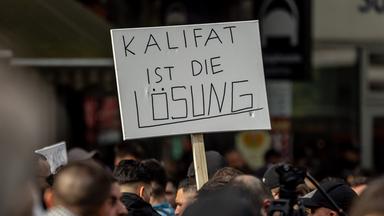 Hamburg: Teilnehmer einer Islamisten-Demo halten ein Plakat mit der Aufschrift "Kalifat ist die Lösung" in die Höhe.