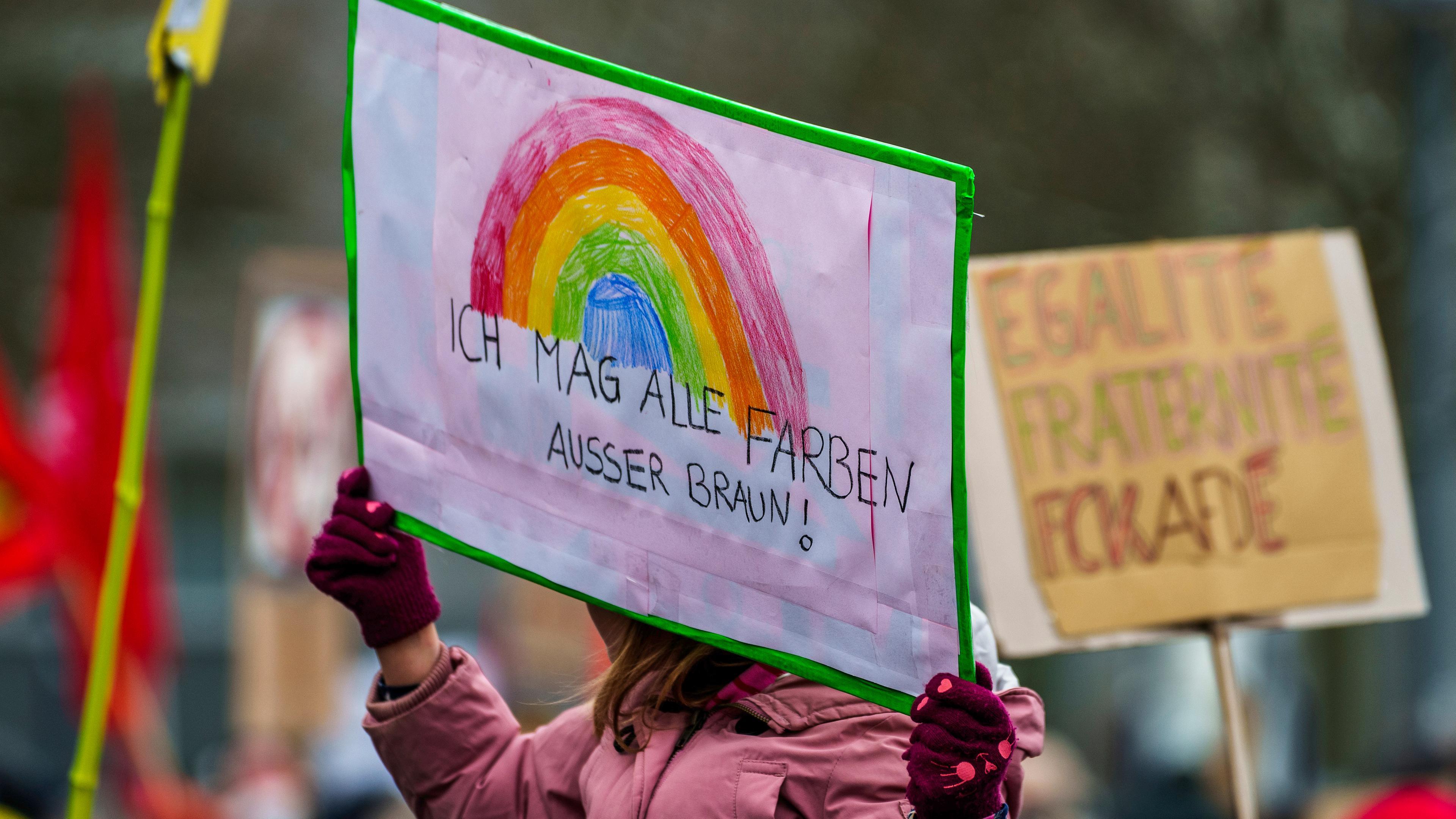 Ein Plakat "Ich mag alle Farben außer Braun!" wird auf einer Kundgebung gegen Rechtsextremismus vor dem Rathaus hochgehalten am 21.01.2024.