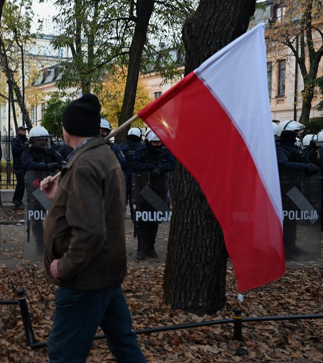 Ein Demonstrant läuft mit der polnische Nationalflagge am 31.10.2026 in Warschau, Polen, an Polizisten vorbei.