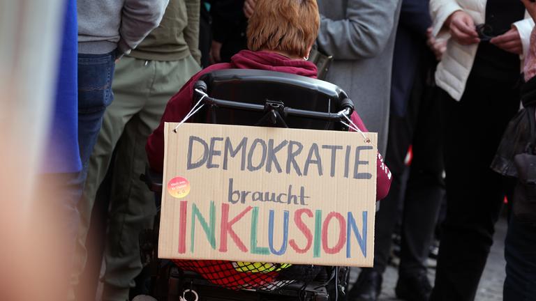 "DEMOKRATIE braucht INKLUSION" ist auf einem an einem Rollstuhl befestigten Plakat bei einer Demonstration gegen rechts in der Innenstadt zu lesen am 03.03.2024 in Würzburg.