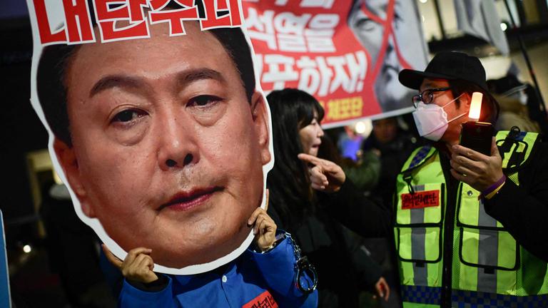 Ein Demonstrant mit einer Pappe, auf der das Gesicht des südkoreanischen Präsidenten Yoon Suk Yeol abgebildet ist