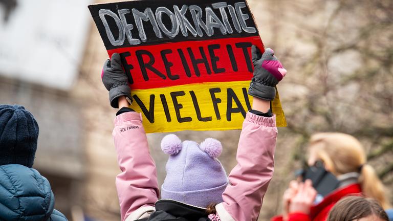 Schleswig-Holstein, Lübeck: "Demokratie - Freiheit - Vielfalt" steht auf einem Schild in den Farben schwarz, rot und gold bei einer Demonstration gegen Rechtsextremismus und die AfD in der Innenstadt.