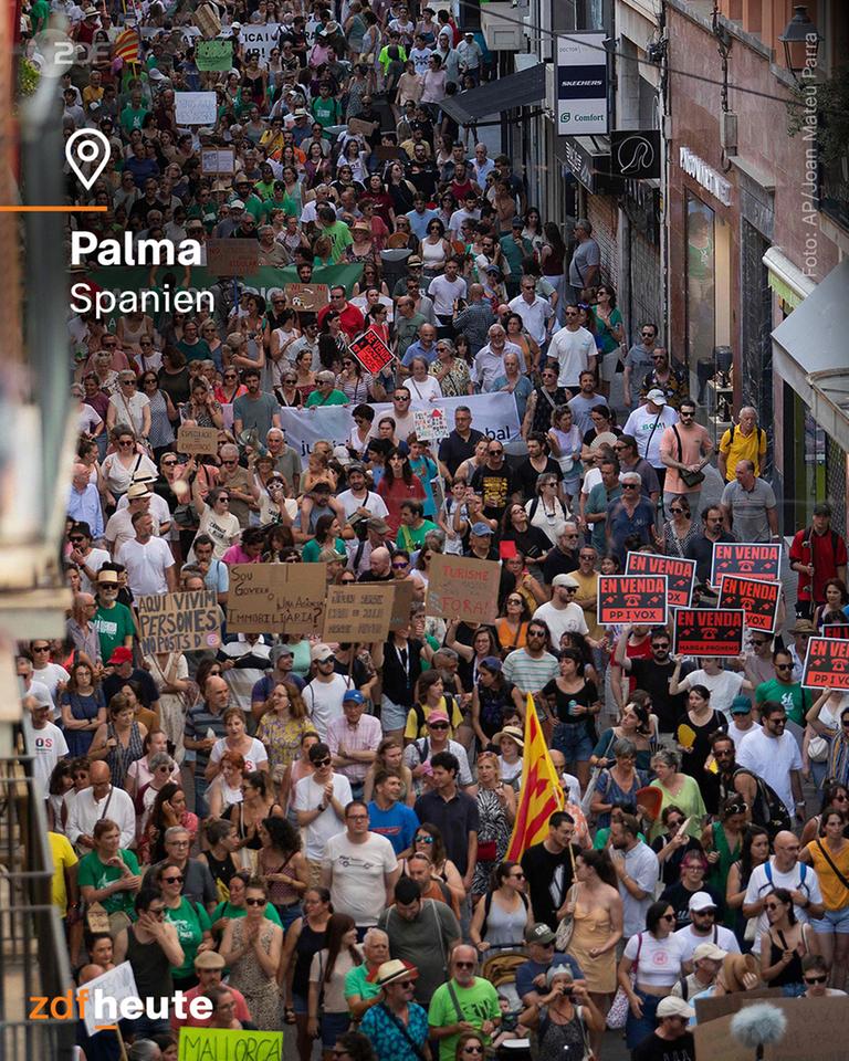 In Palma in Spanien zieht eine Menschenmenge durch eine Straße und protestiert gegen Massentourismus.