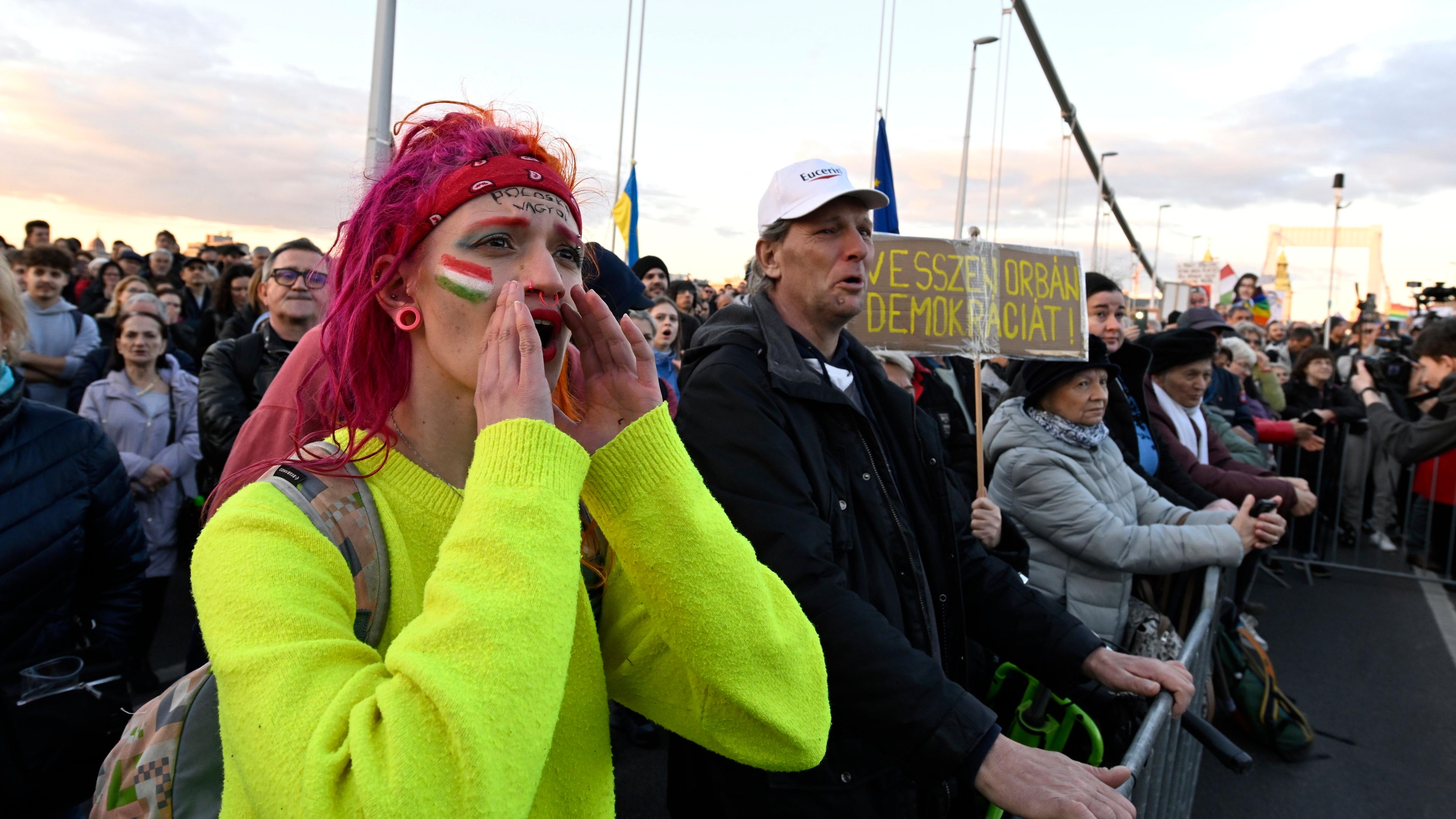 Tasusende protestieren in Budapest gegen das beschlossene Verbot der jährlichen Pride-Parade. Eine gelb gekleidete Frau ruft vermutlich einen Slogan.